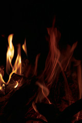 A fire burning with a bright, yellow flame on hot coals on a dark night
