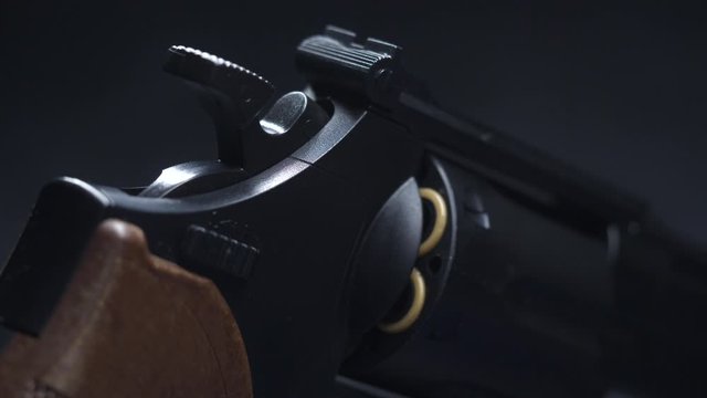 Dramatic Closeup of light illuminating a revolver Pistol Gun on a table in the dark while it passes over it