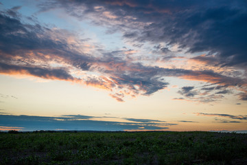 Naklejka na ściany i meble Cloudy sunset over fields summer evening photo