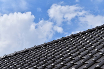 Close up of dark brown ceramic tile roof with blue sky background. Copy space. 