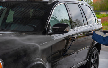 A man is washing a car at self service car wash.