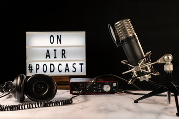 Podcast studio set with microphone, headphones, console and “on air” sign turned on, over...