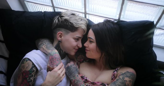 Lesbian couple lying in bed embracing and caressing each other