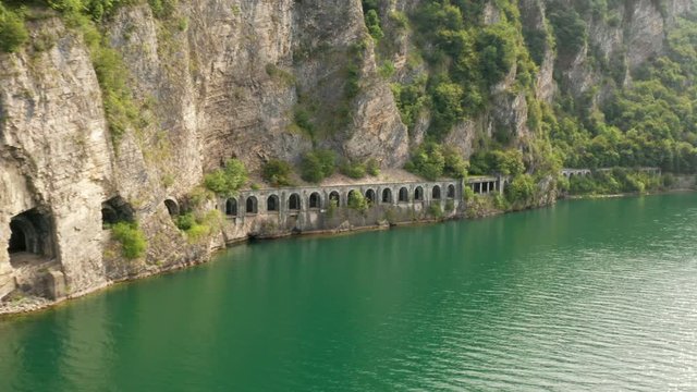 Car road tunnel Grumo in mountain with high green trees near Como Lake. Aerial view of green water and rocks, Olcio, Italy. 