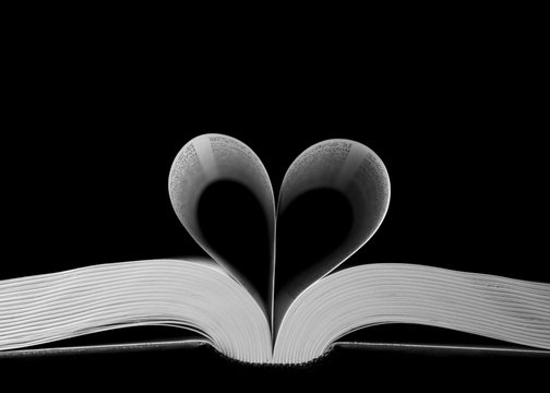 Closeup shot of heart-shaped book pages on a black background