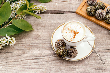 Сup of coffee and protein homemade sweets made from boiled lentils,cocoa powder, peanut paste, dates and decorated with nuts on a wooden background.Сoncept of healthy food and healthy desserts.