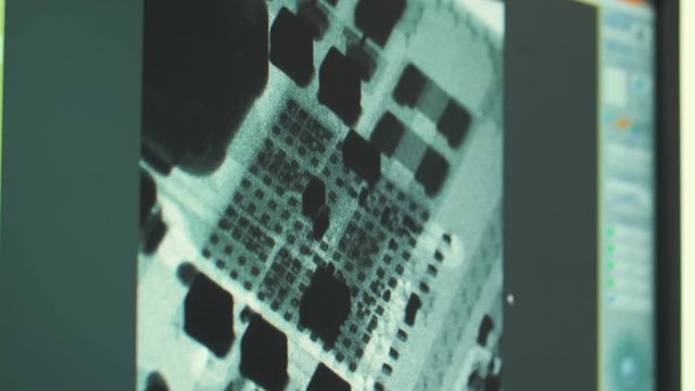 Lab technician examines an x-ray image of a microcircuit on a computer screen.