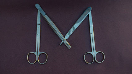 tijeras y pinzas quirúrgicas formando una letra M