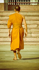 Monk in orange with barefoot on ground