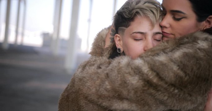 Lesbian couple hugging each other in a city street