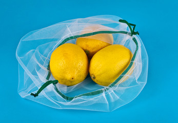 Lemons in a reusable eco friendly net bag on a blue background.