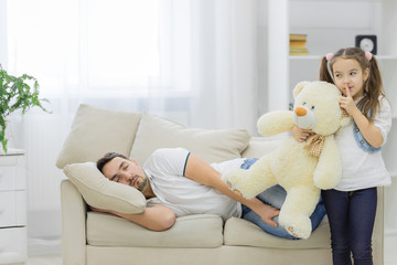Father is sleeping and his daughter holds a white bear.