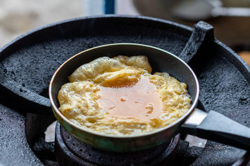 Fried omelette in a small pan on the old gas stove.
