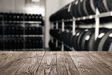 Empty wooden surface and blurred view of car tires in auto store, closeup. Space for text © New Africa