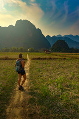 Fototapeta na wymiar Vang Vieng Laos Girl Hiking at sunset towards limestone mountains