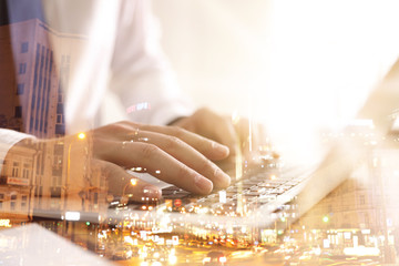 Double exposure of male programmer using laptop and cityscape, closeup