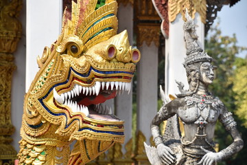 Golden Dragon Head in Foreground with Standing Statue in Background, Facing Right, Wat Chang Kham, Chiang Mai