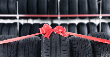 Car tires tied with red ribbon in auto store. Banner design © New Africa