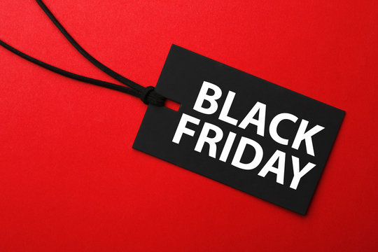Tag with text BLACK FRIDAY on red background, top view