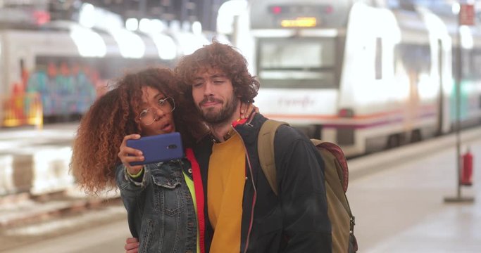 Multi-ethnic couple taking selfie with smartphone at train station