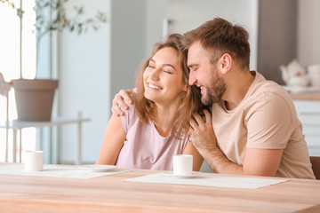 Happy young couple drinking tea in kitchen