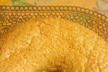 Big bagel with sesame seeds close-up on a decorative background with gold lace