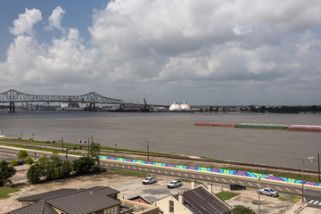 Looking across the Mississippi river to a industrial plant next to a long bridge on a bright day