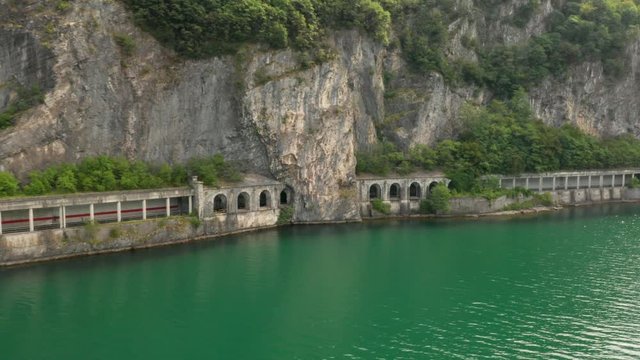Aerial shooting along Grumo tunnel in granite mountain with green trees next to Como Lake, Lecco, Italy 