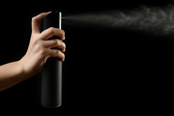 Female hand with hair spray on dark background