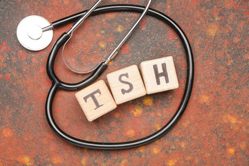Cubes with abbreviation TSH and stethoscope on color background