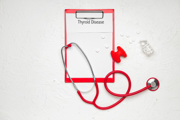 Clipboard with text THYROID DISEASE, pills and stethoscope on white background