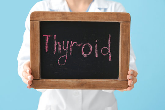 Doctor holding chalkboard with text THYROID, closeup. Concept of thyroid disease
