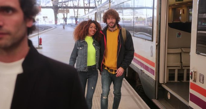 Multi-ethnic couple leaving train on platform at train station