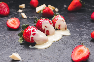 Tasty strawberry with melted chocolate on dark background
