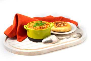 A bowl of hearty barley soup in a green bowl is served with flat bread  and orange linen napkin.