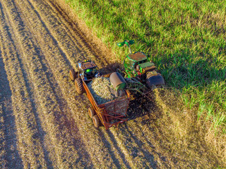 Farm Tractors working on sugar cane harvest plantation aerial view 