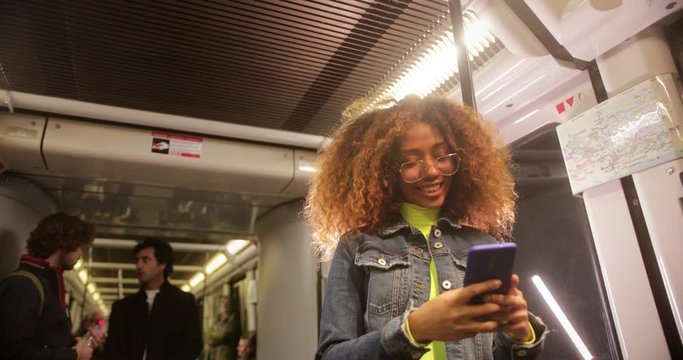 Young black woman using smartphone while travelling on train
