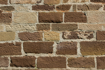 Brick wall made out of brown and beige sandstone blocks