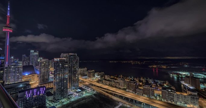 Wide angle Toronto Ontario, Canada down town night time-lapse, from a high rise building facing lake Ontario, the island, the airport and the Gardiner Expressway. CN Tower visible at the edge of frame