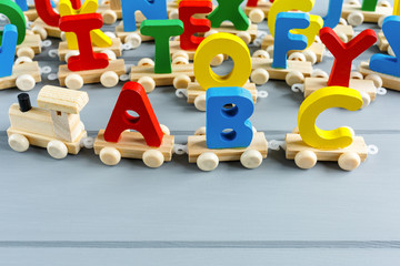 Close up Multicolored wooden letters with ABC on gray background. Set of toys for studying alphabet. Education, back to school concept. Top view, copy space	