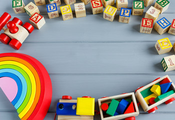 Close up Multicolored wooden cubes with letters, pencils, rainbow arc on gray background. Set of toys for studying alphabet. Education, back to school concept. Top view, copy space