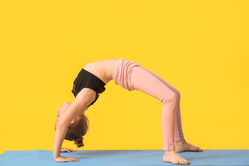Little girl practicing yoga on color background