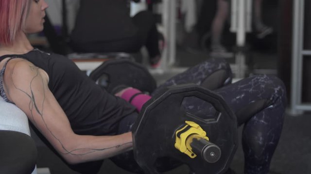 Woman performs weighted hip thrust in gym, profile, slow-mo