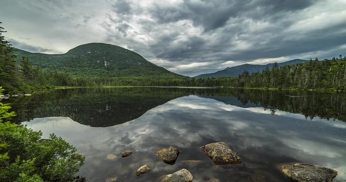 Wide angle day time-lapse over the mirror like, lonesome lake in New Hampshire, USA, with a mountainous landscape in the background. Includes 2 shots.