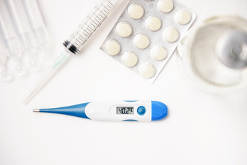 Pills, thermometer and syringes on white background. Coronavirus (COVID-19) epidemic. Flat lay, top view, copy space.