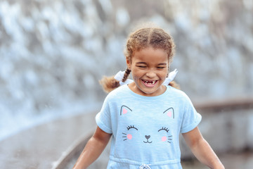 Happy beautiful girl running through the spray of water.