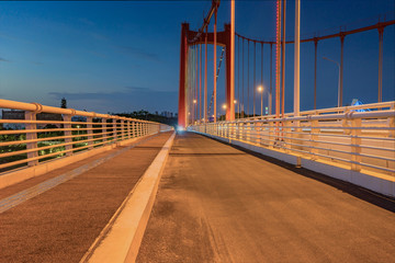 Fototapeta na wymiar Perspective view of night road of large suspension bridge