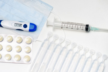 Pills, thermometer and syringes on white background. Coronavirus (COVID-19) epidemic. Flat lay, top view, copy space.