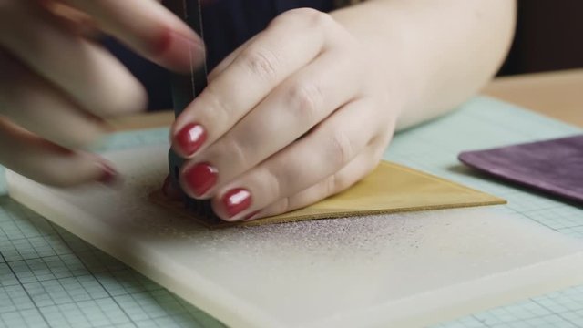 Close-up of a woman crafting with leather on a handmade project.