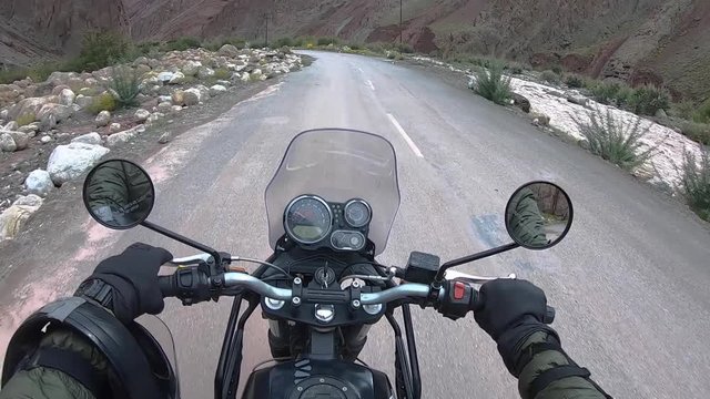 bike riding wide angle shot on a wet, muddy, and slippery mountain road with high barren mountains in the surrounding.